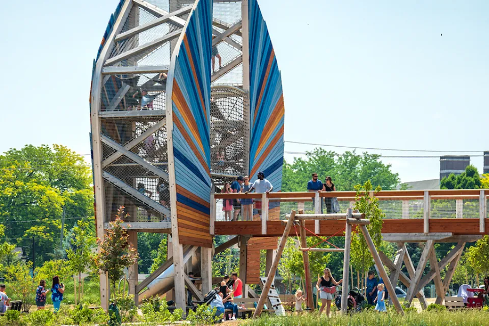 Large wood structure with bridge and people standing on it in green park in Toledo, Ohio.